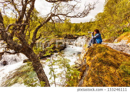 Tourist with camera at river, Norway Tourist with camera at river, Norway 133246111