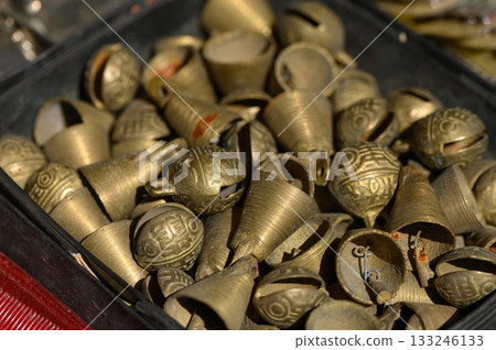 Intricate metal bells shine in the afternoon light at a bustling local market in India 133246133