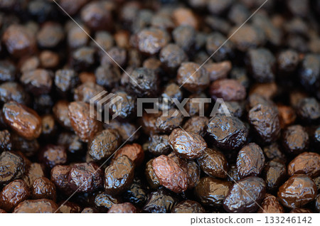 Dark and glossy dried fruits create a rich tapestry of textures in a rustic market setting 133246142