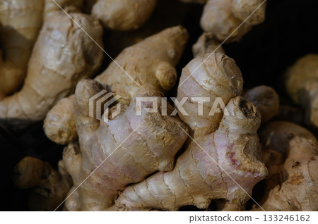 Fresh organic ginger roots piled together in a dimly lit market stall ready for culinary use Fresh organic ginger roots piled together in a dimly lit market stall ready for culinary use 133246162