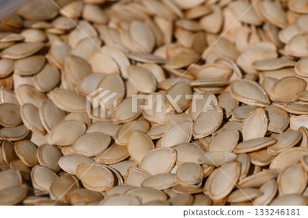 Pumpkin seeds spread out in natural light showcasing their unique shapes and textures 133246181