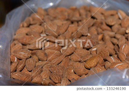 Almonds nestled in a clear bag, showcasing their natural texture and earthy tones Almonds nestled in a clear bag, showcasing their natural texture and earthy tones 133246190