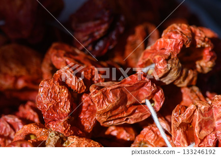 Dried red peppers basking in sunlight, showcasing vibrant colors and unique textures in a quaint kitchen 133246192