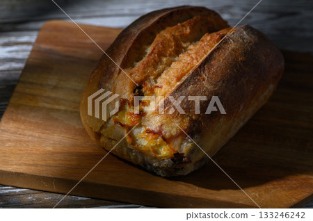 Freshly baked artisan bread on a rustic wooden cutting board in warm afternoon light Freshly baked artisan bread on a rustic wooden cutting board in warm afternoon light 133246242