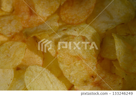 Crunchy golden potato chips scattered in a bowl create a tempting snack experience at any gathering 133246249