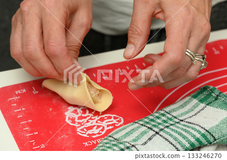 Delicate hands craft a savory pastry with care in a cozy kitchen during late afternoon Delicate hands craft a savory pastry with care in a cozy kitchen during late afternoon 133246270