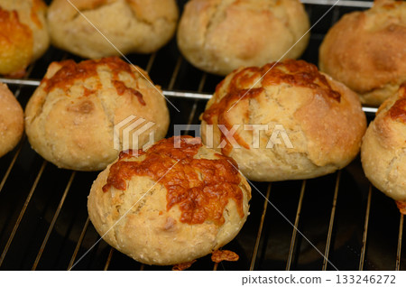 Freshly baked cheese rolls cooling on a wire rack in a cozy kitchen Freshly baked cheese rolls cooling on a wire rack in a cozy kitchen 133246272