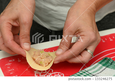 Hands skillfully prepare a delicious filling wrapped in dough for a delightful culinary creation 133246275