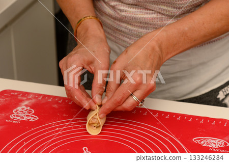 Crafting delicate dumplings in a cozy kitchen filled with warmth and flour 133246284