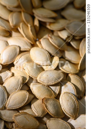 Pumpkin seeds piled together in a warm light, showcasing their natural texture and beauty in autumn's embrace 133246309