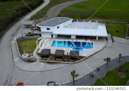Luxury villa with a sparkling pool surrounded by lush greenery in a serene landscape at dusk Luxury villa with a sparkling pool surrounded by lush greenery in a serene landscape at dusk 133246501