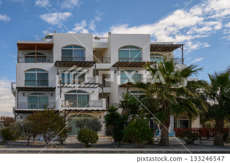 Beautiful seaside villa surrounded by lush greenery on a sunny day in a coastal town Beautiful seaside villa surrounded by lush greenery on a sunny day in a coastal town 133246547