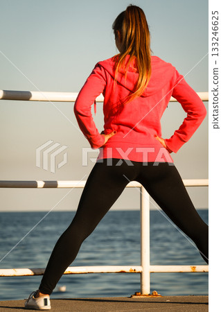 Woman jogger stretches on pier by seaside Woman jogger stretches on pier by seaside 133246625