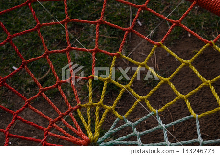 Colorful netting stretches across a grassy field under the afternoon sun Colorful netting stretches across a grassy field under the afternoon sun 133246773