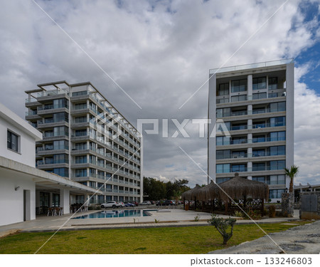 Modern resort buildings under a cloudy sky with a serene poolside view in a tranquil vacation destination 133246803