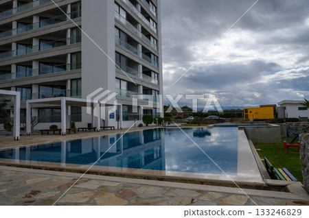 Cloudy afternoon by the tranquil poolside of a modern building in a serene setting 133246829
