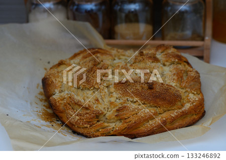 Freshly baked loaf with a golden crust placed on parchment paper in a rustic kitchen setting Freshly baked loaf with a golden crust placed on parchment paper in a rustic kitchen setting 133246892