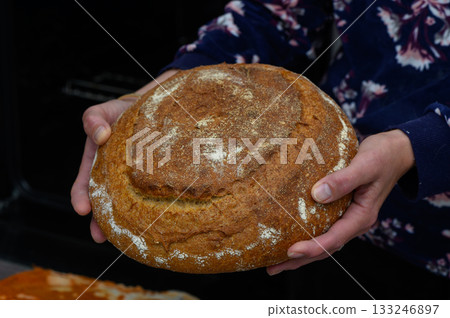 Freshly baked artisanal bread being presented with pride in a cozy kitchen atmosphere Freshly baked artisanal bread being presented with pride in a cozy kitchen atmosphere 133246897