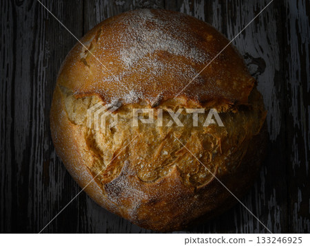 Golden crusted bread rests on a rustic wooden surface under soft warm lighting Golden crusted bread rests on a rustic wooden surface under soft warm lighting 133246925