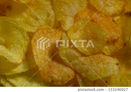 Crispy golden potato chips scattered in an inviting bowl during an afternoon snack session 133246927