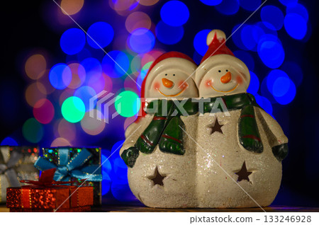 Joyful snowmen sharing holiday cheer beside colorful festive lights Joyful snowmen sharing holiday cheer beside colorful festive lights 133246928