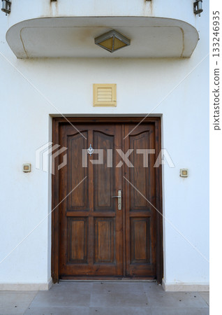 Classic wooden door framed by simple architecture invites exploration on a bright sunny day 133246935