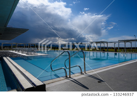 Beautiful poolside view under dramatic clouds at a sunny afternoon retreat 133246937