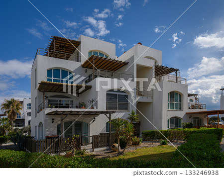 Elegant coastal villa with modern architecture overlooking lush gardens and blue sky Elegant coastal villa with modern architecture overlooking lush gardens and blue sky 133246938