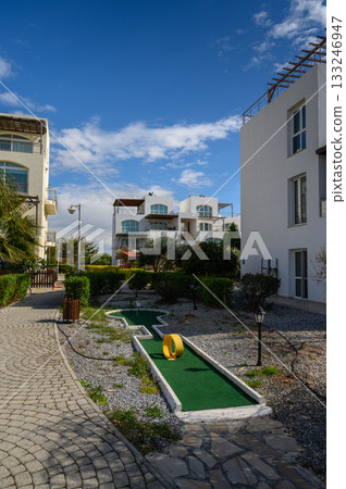 Mini golf course nestled between modern buildings under a sunny sky Mini golf course nestled between modern buildings under a sunny sky 133246947