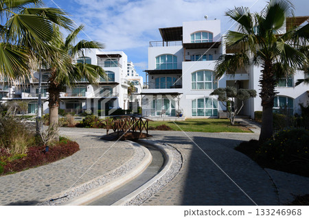 Serene morning stroll through a modern coastal community adorned with palm trees and winding pathways Serene morning stroll through a modern coastal community adorned with palm trees and winding pathways 133246968