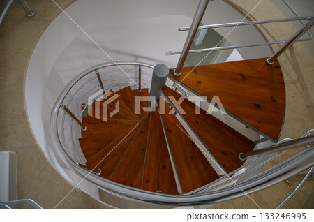 Spiral staircase crafted with wooden steps and metal railings creating an elegant design 133246995