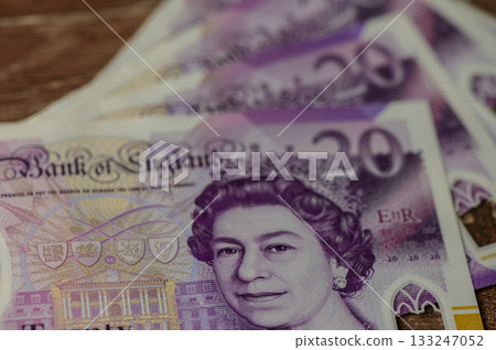 Currency showcasing the intricate designs of UK twenty-pound notes on a wooden surface Currency showcasing the intricate designs of UK twenty-pound notes on a wooden surface 133247052