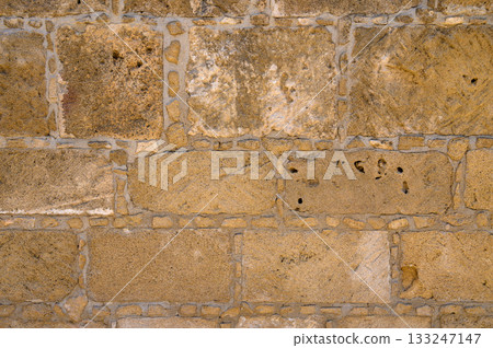Texture of aged stone wall with warm tones and intricate details from a historic building Texture of aged stone wall with warm tones and intricate details from a historic building 133247147