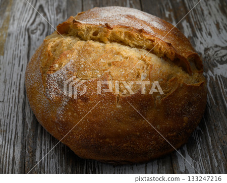 Freshly baked crusty bread resting on rustic wooden table inviting warmth and comfort 133247216