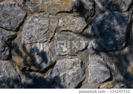 Nature's artistry reveals the beauty of a stone wall under sunlight and shadow Nature's artistry reveals the beauty of a stone wall under sunlight and shadow 133247532
