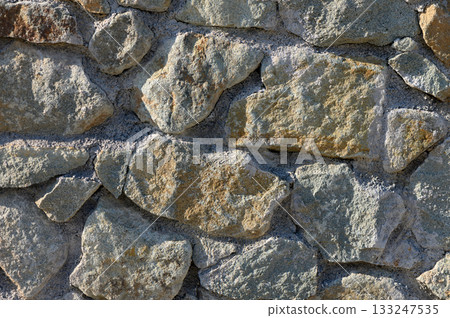 Rustic charm of a weathered stone wall in the heart of a countryside landscape under bright sunlight 133247535