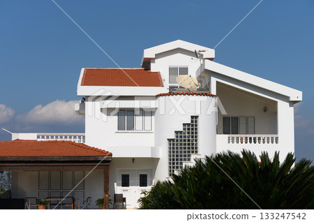 Modern white villa with unique architecture set against a clear blue sky in a tranquil neighborhood Modern white villa with unique architecture set against a clear blue sky in a tranquil neighborhood 133247542