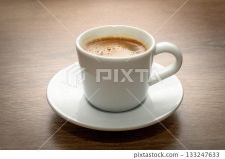 Freshly brewed Turkish coffee in cup on wooden table Freshly brewed Turkish coffee in cup on wooden table 133247633