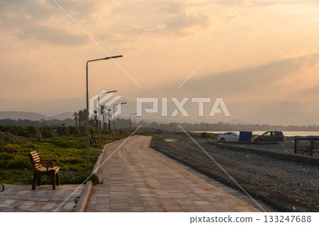 Golden hour captures serene pathway beside the water, inviting quiet contemplation and reflection in nature's embrace 133247688