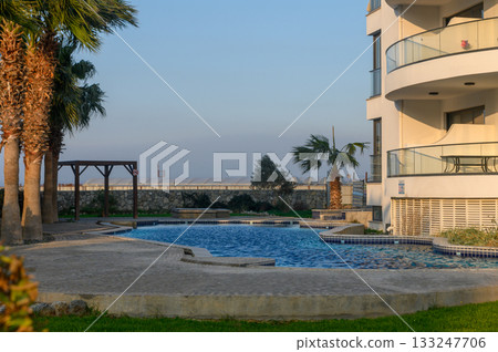 Serene afternoon at a luxurious poolside retreat with lush greenery and stunning views 133247706