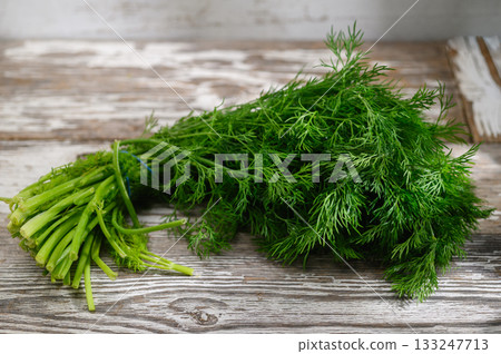Freshly harvested dill resting on a rustic wooden surface with textured patterns in natural light Freshly harvested dill resting on a rustic wooden surface with textured patterns in natural light 133247713