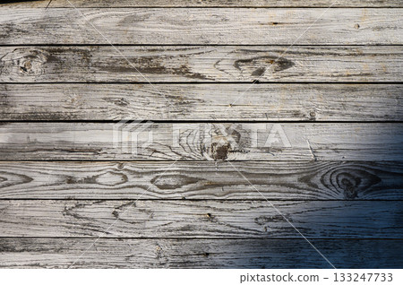 Weathered wood planks create a rustic tapestry of texture and character in warm afternoon sunlight 133247733