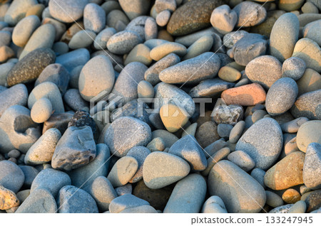 Colors and textures of smooth pebbles on a serene beach at sunset 133247945