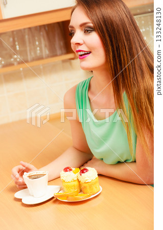 Woman with coffee and cake in kitchen. Gluttony. 133248130
