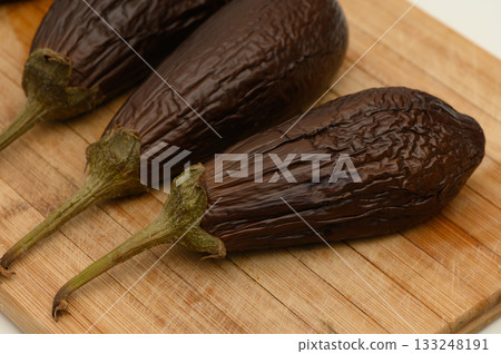 Smoky roasted eggplants resting on a wooden cutting board after being prepared for a savory dish Smoky roasted eggplants resting on a wooden cutting board after being prepared for a savory dish 133248191