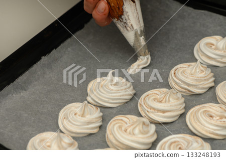 Beautifully crafted meringue swirls form an exquisite dessert display in a cozy kitchen Beautifully crafted meringue swirls form an exquisite dessert display in a cozy kitchen 133248193