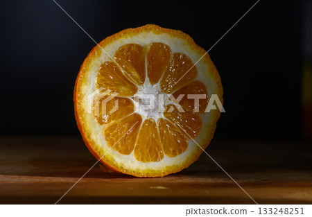 Bright orange citrus fruit slice showcasing vibrant segments on a wooden surface Bright orange citrus fruit slice showcasing vibrant segments on a wooden surface 133248251