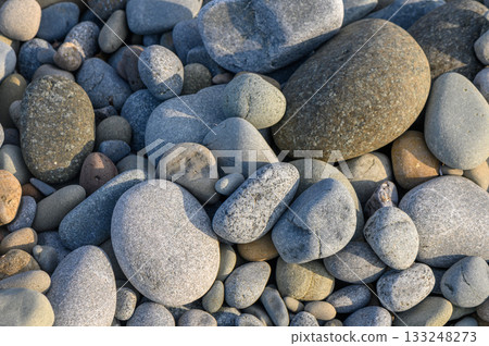Textures of nature captured through a collection of smooth pebbles along a serene riverbank 133248273