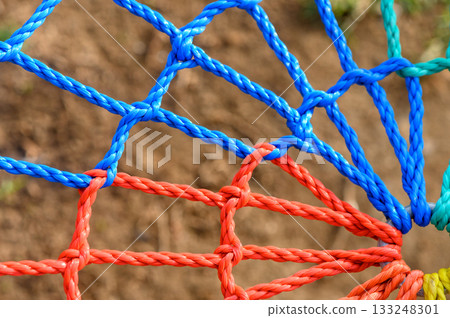 Vibrant colors of woven ropes create an intricate pattern in a sunny garden setting 133248301
