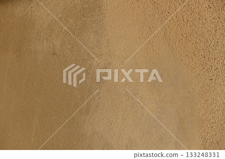 Texture of warm earth tones on a sunlit wall evokes a sense of calm and natural simplicity 133248331